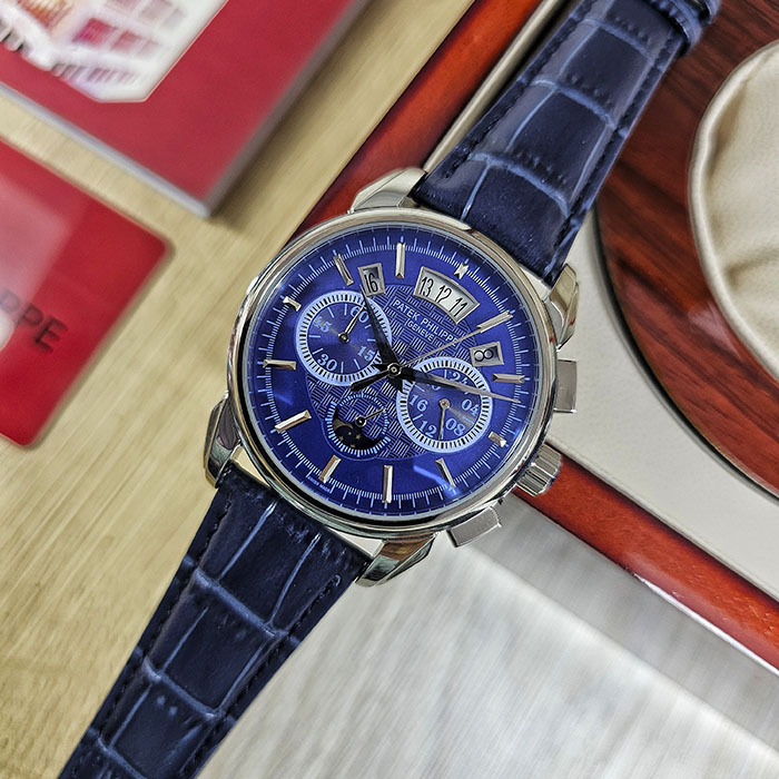 Réplica AAA Patek Philippe en caja de acero con rica esfera azul rey, grabado guilloché central, fase lunar y correa de cuero azul.