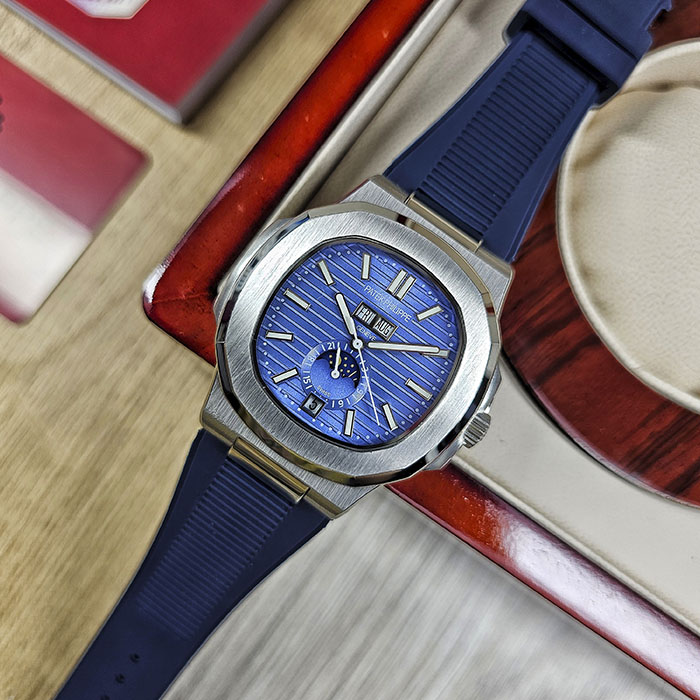 Réplica AAA Patek Philippe Nautilus en caja de acero con esfera azul acanalada, calendario anual, fase lunar y correa de caucho azul.