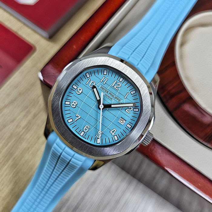 Réplica de reloj Patek Philippe Aquanaut calidad AAA en acero con vibrante esfera azul turquesa, fechador a las 3 y correa de caucho turquesa.