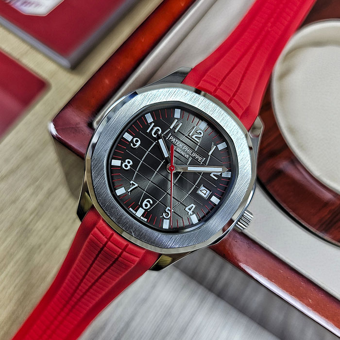 Réplica AAA Patek Philippe Aquanaut en caja de acero con esfera negra cuadriculada, segundero rojo, fechador y correa de caucho roja.