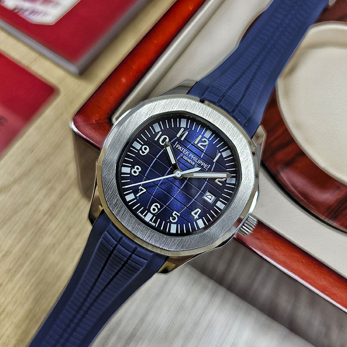 Réplica AAA de reloj Patek Philippe Aquanaut en caja de acero con esfera azul marino acanalada, fechador y correa de caucho azul marino.