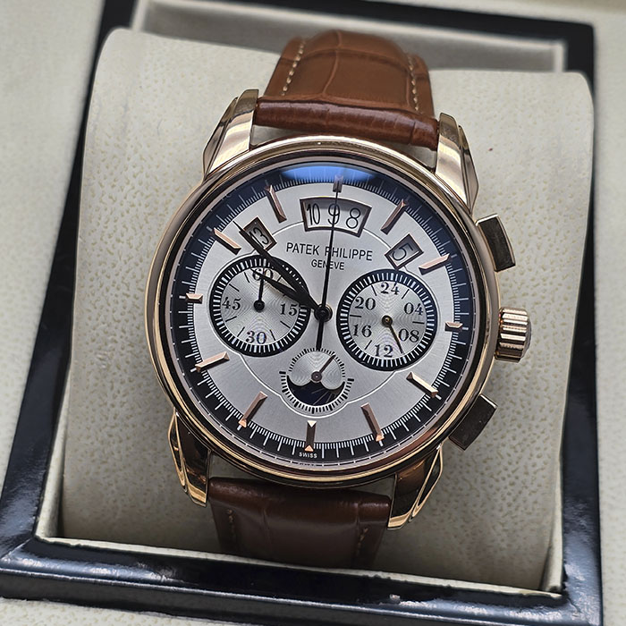 Réplica AAA de reloj Patek Philippe en caja de oro rosa con dial plateado cepillado, anillo exterior negro, subesferas de cronógrafo y correa de cuero marrón.