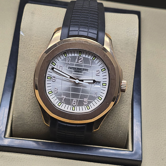 Réplica AAA de reloj Patek Philippe Aquanaut en caja de oro rosa con esfera gris mapa mundi, números arábigos y correa de caucho negra.