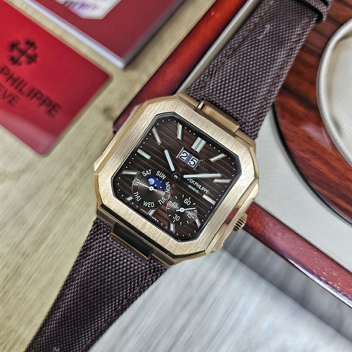 Réplica AAA Patek Philippe Cubitus en caja de oro rosa con esfera marrón acanalada, gran fechador, fase lunar y correa textil marrón.