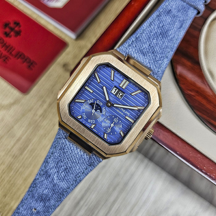 Réplica de reloj Patek Philippe Cubitus calidad AAA en oro rosa con esfera azul acanalada, gran fecha y correa de tela vaquera azul.