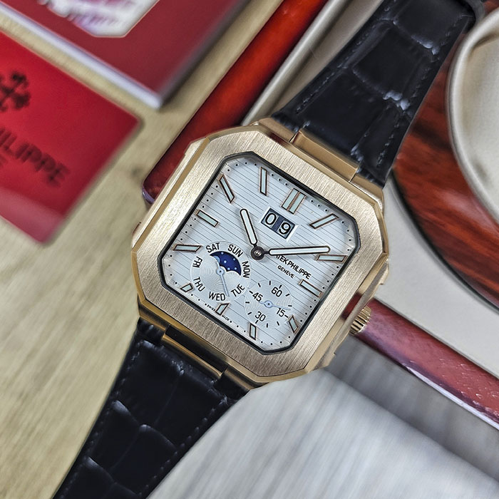 Réplica AAA Patek Philippe Cubitus en caja de oro rosa con pulcra esfera blanca acanalada, gran fecha, fase lunar y correa de cuero negra.